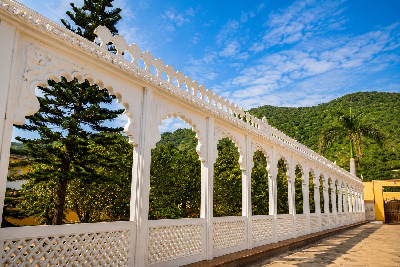 A white colonnade walkway with hill views