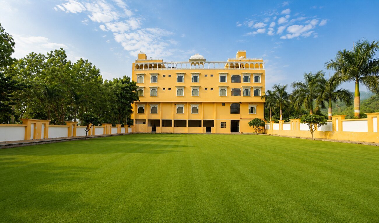 The yellow palace-style Dream Hills Resort building beside its lush green lawn under a blue sky