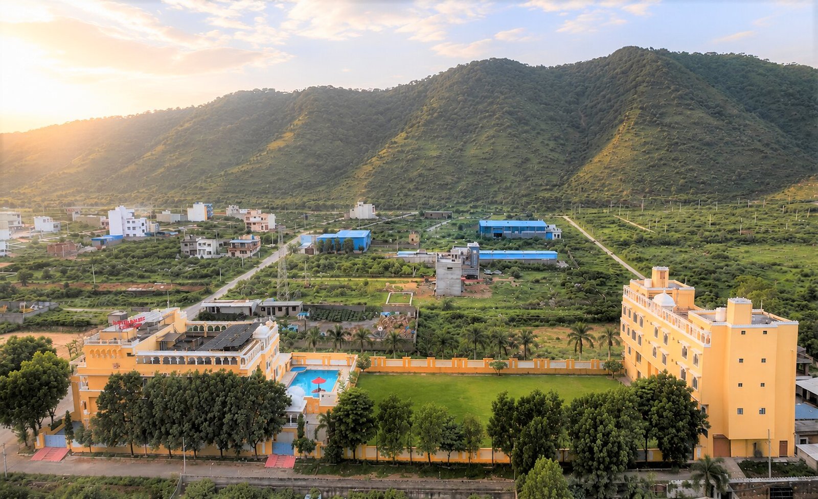 Dream Hills Resort glowing at golden hour with the Aravalli hills behind it in Udaipur